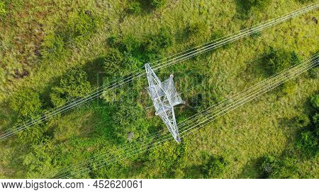Aerial Top Down View High Voltage Steel Power Pylons In Green Field Countryside. Flight Over Power T