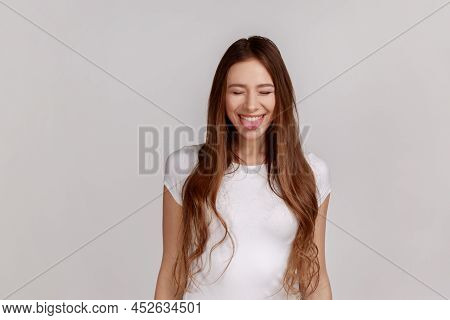 Portrait Of Positive Playful Woman Standing With Closed Eyes And Tongue Out, Demonstrating Childish 
