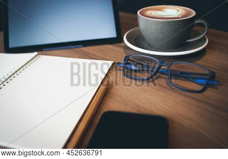 Work From Home, Desk Office With Digital Tablet, Blank Notepad, Eye Glasses, Mobile Phone And Coffee
