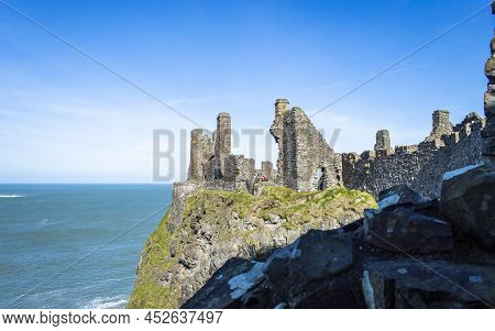 Bushmills, Northern Ireland, March 18, 2022. Dunluce Castle On The Cliff With Blue Sea Background In