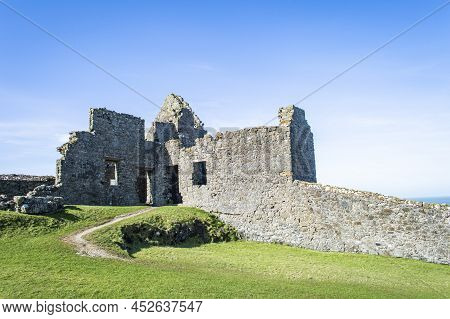 Bushmills, Northern Ireland, March 18, 2022. Dunluce Castle Ruins At Northern Ireland In A Sunny Day