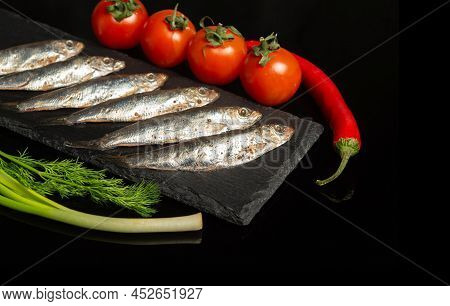 Sea Sprat With Vegetables On A Serving Blackboard. Small Salted Fish With Onions And Tomatoes. Delic