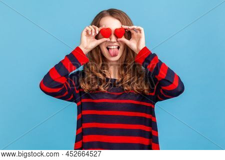 Funny Woman Wearing Striped Casual Style Sweater, Covering Eyes With Small Red Hearts And Showing To