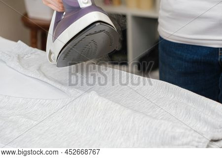 A Woman Irons Clothes With An Iron With A Steam Generator. Steam From The Iron, Steaming Clothes, Ce
