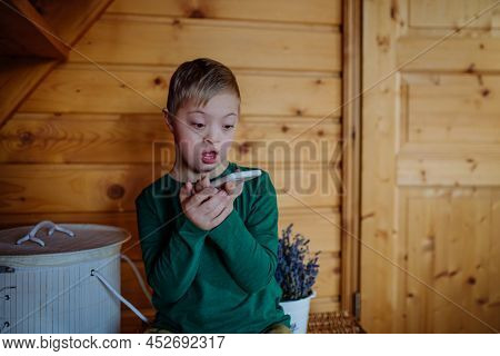 Surprised Little Boy With Down Syndrome Using Smartphone At Home