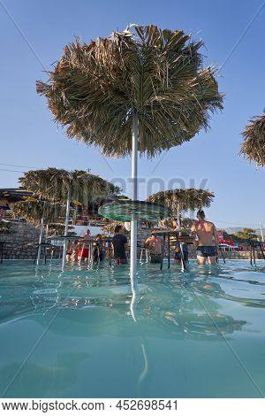 Budva, Montenegro - July 30, 2021: A Table With An Umbrella Made Of Palm Leaves In A Ploce Beach Bar