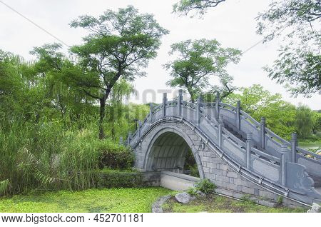 A Curved Bridge Over A Wetland Within The Jinshan Temple Scenic Area On A Cloudy Day In Zhenjiang Ch