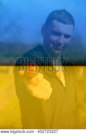 Defocus Ukrainian Young Man Holding One Colored Red Egg On Nature Background. Easter, Ukraine Flag. 