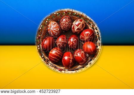 Defocus Closeup Of Basket Of Colored Red Eggs On Nature Green Grass Background. Easter Holiday Conce