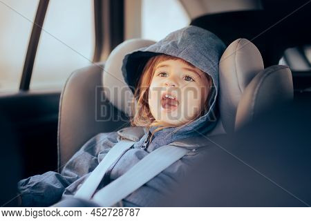 Cheerful Child Sitting In Car Chair Ready To Travel