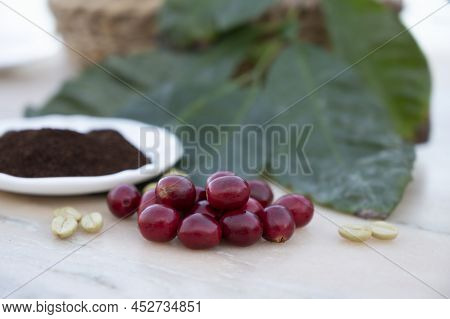 Red Ripe Arabica Coffee Berries, Green Coffee Beands, Leaves And Roasted Ground Coffee In Bowl