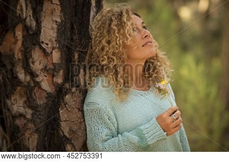 Thoughtful Pretty Adult Caucasian Lady Holding Flower In Hand And Looking In The Air In Relax Leisur