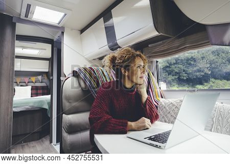 Adult Woman Use Laptop Computer Inside A Camper Van Recreational Vehicle Sitting At The Table With B