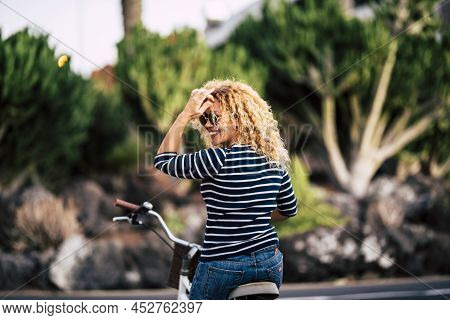 Hipster Woman With Curly Hair And Sunglasses Sitting On Bicycle Looking Over Shoulder And Admiring S