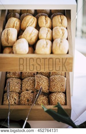 Bread Buns In Abundance On Display At Slatted Shelf Fixture In Hotel Or Supermarket For Sale. Freshl