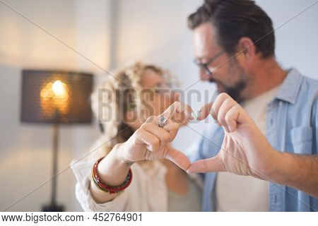 Cheerful Couple Embracing While Doing Heart Shape Gesture With Hands. Happy Couple Posing In Front O