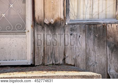Close Up Of Weathered Wood Siding Beginning To Rot Around Front Step Of Cottage Or House