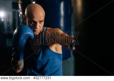 Close-up Of Professional Bald Boxer Male Training Punches, Beating Punching Bag In Sport Club With D