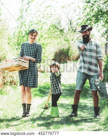 Happy Family: Mother, Father, Children Son On Spring Garden Background. Family Gardening In The Back