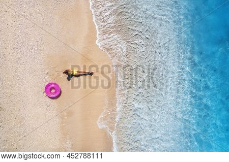 Aerial View Of Young Woman With Pink Swim Ring On The Sandy Beac