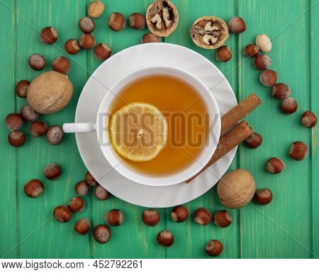 Top View Of Cup Of Hot Toddy With Lemon Inside And Cinnamon On Saucer With Pattern Of Nuts And Walnu