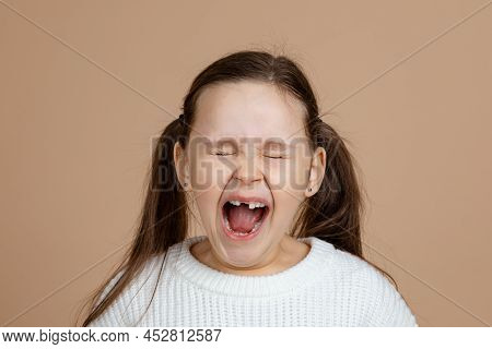 Portrait Of Young Furious Angry Girl With Long Dark Hair In Pink, White Sweater Standing With Closed