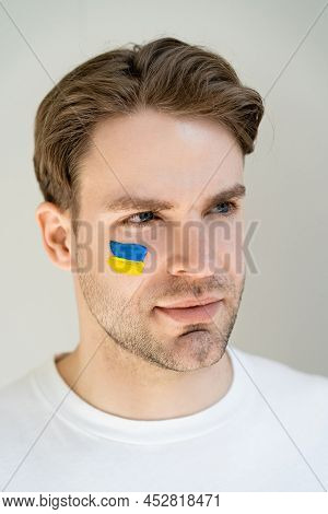 Portrait Of Patriotic Man With Unkrainian Flag Painted On Face Isolated On Grey