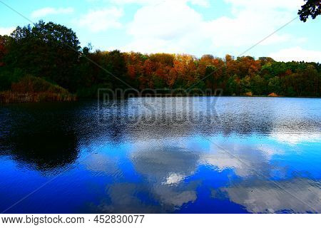 Reflected Clouds In Blue Caldera Lake Holzmaar, Eifel