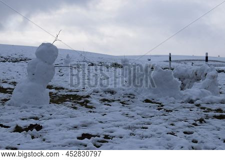 Snow Men Slowly Melting Away On A Grey Winter Day