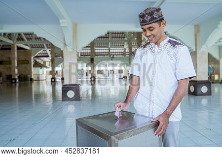 Muslim Paying Some Zakat Charity Using Cash At The Mosque
