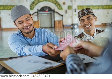 Muslim Paying Some Zakat Charity Using Cash At The Mosque
