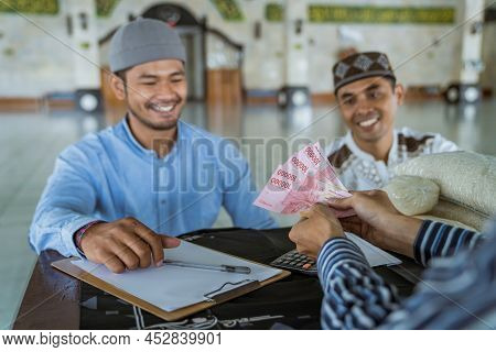 Muslim Paying Some Zakat Charity Using Cash At The Mosque