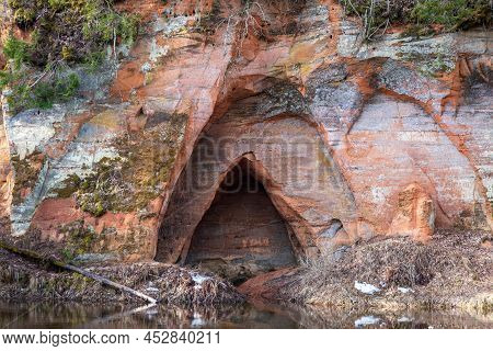 View To The Angels Cave, A Red Sandstone Cliff At The River Salaca In Skanaiskalns Nature Park In Ma