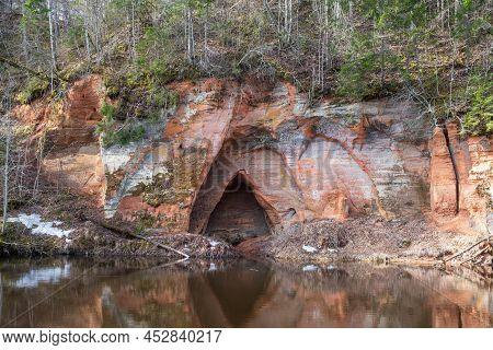View To The Angels Cave, A Red Sandstone Cliff At The River Salaca In Skanaiskalns Nature Park In Ma