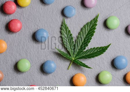 Cannabis Leaf With Colorful Candy Confetti Close Up. Marijuana Sweets With Cbd And Thc On Gray 
Back