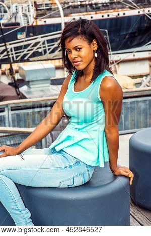 African American Woman Traveling In New York, Wearing Green Tank Top, Blue Fashionable Jeans, Sittin