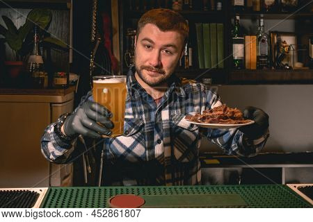 Friendly Bearded Bartender Offering Glass Of Beer With Snacks In Pub