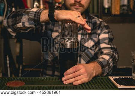 Professional Bartender Making Cocktail For Guests In Shaker