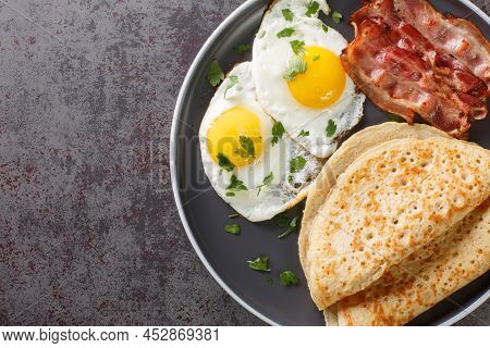 Staffordshire Oatcakes With Bacon And Fried Eggs Close-up In A Plate On The Table. Horizontal Top Vi