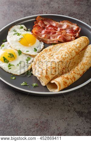 English Breakfast Of Bacon, Eggs And Oatcakes Oat Pancakes Close-up In A Plate On The Table. Vertica