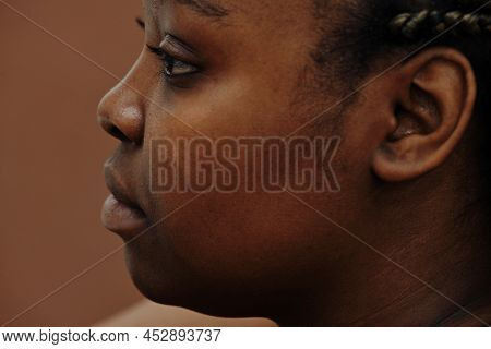 Side View Of African Young Woman Face Looking Away Isolated On Brown Background