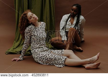 Young Sensual White Woman Relaxing On Floor With Black Woman Sitting In Background
