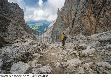 Man In Yellow Jacket And Backpack At Pass On Mountain Sassolungo - Langkofel, Alpe Di Siusi, Dolomit