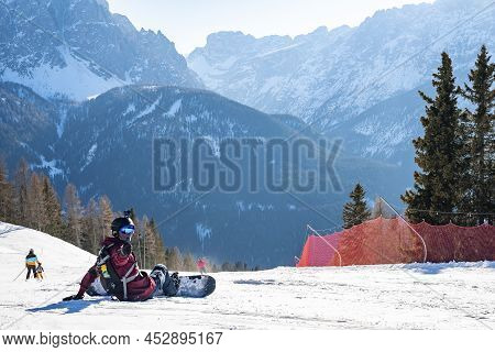Portrait Of Snowboarder Gesturing Thumbs Up While Sitting On Snowy Landscape