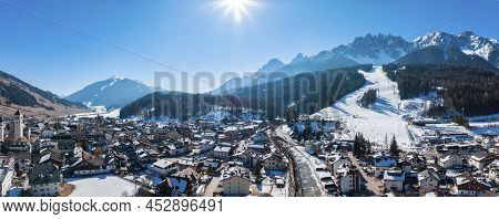 Panoramic View Of Sun Shining Over Mountain Range And Townscape During Winter