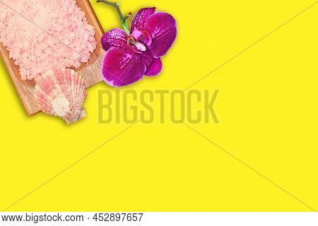 Wooden Bowl With Pink Sea Salt And Purple Orchid On Yellow Background. Beauty And Spa. Copy Space