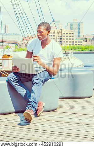 Young African American Man Traveling In New York, Wearing White T Shirt, Blue Pants, Boot Shoes, Sit