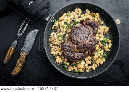 Rib Eye Steak With Herbs, Roasted Beans, Thyme And Garlic Set, On Frying Cast Iron Pan, With Meat Kn