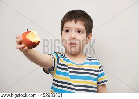 A 4 Year Old Boy Eats A Red Apple And Squirms. The Child Does Not Like Fruit