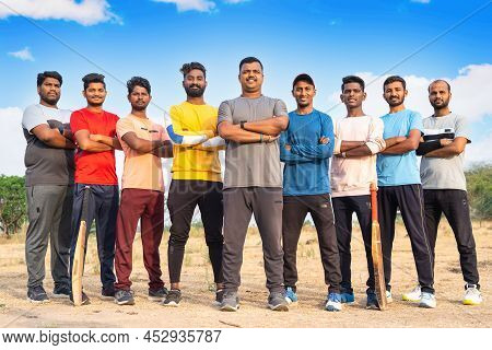 Fullshot, Group Of Confident Cricket Players Standing With Arms Crossed By Looking Camera At Playgro